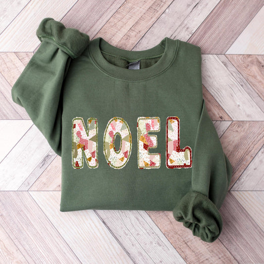 A military green Gildan crewneck sweatshirt with NOEL printed on it in a muted sage, maroon, and white patchwork pattern.