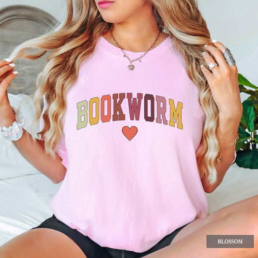 Person wearing a pink 'BOOKWORM' t-shirt with colorful text and a heart symbol.