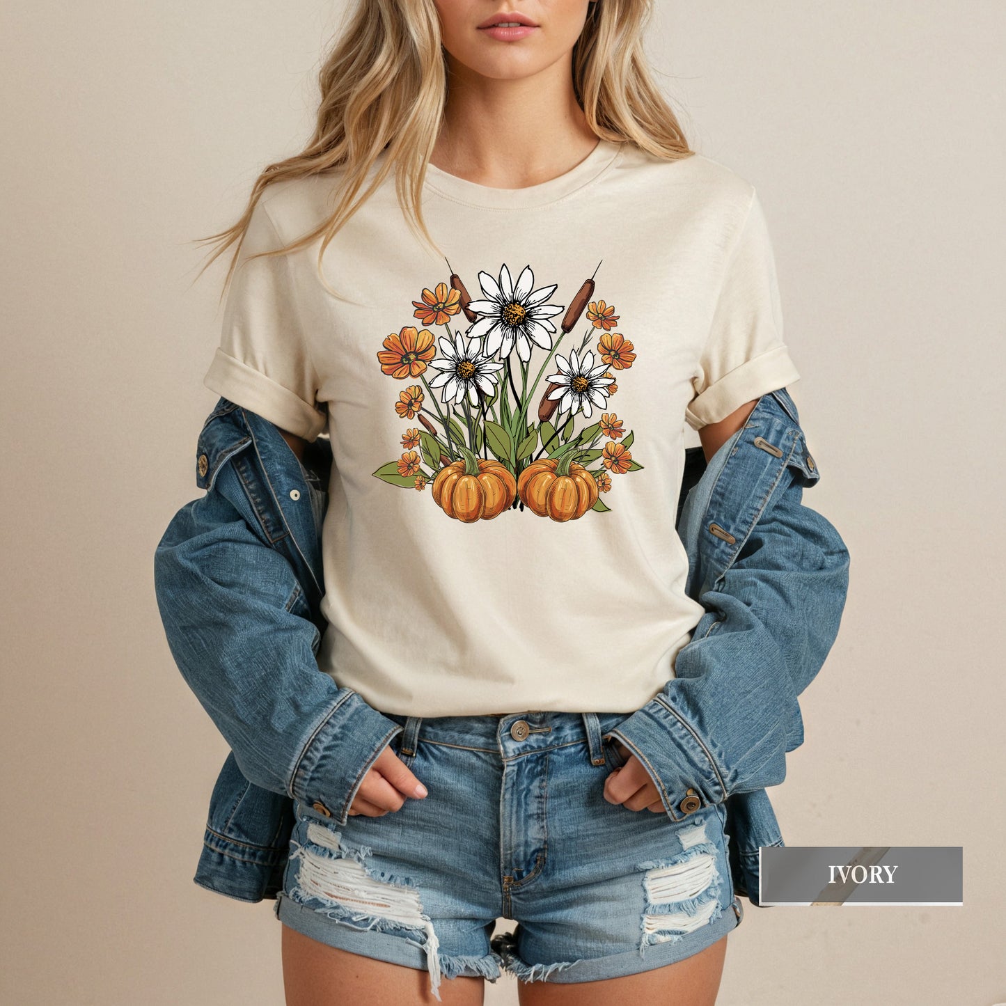Person wearing a white t-shirt with a floral and pumpkin design, paired with a denim jacket and shorts.