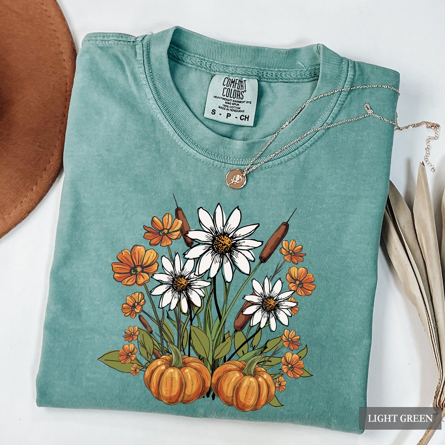 Light green t-shirt with floral and pumpkin design on a white background