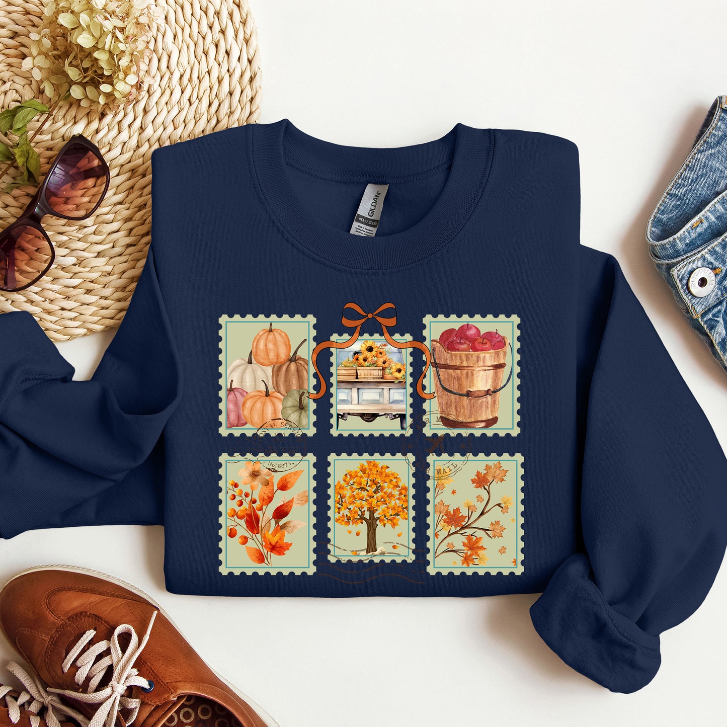 Navy blue sweatshirt with autumn-themed design on a white surface with accessories.