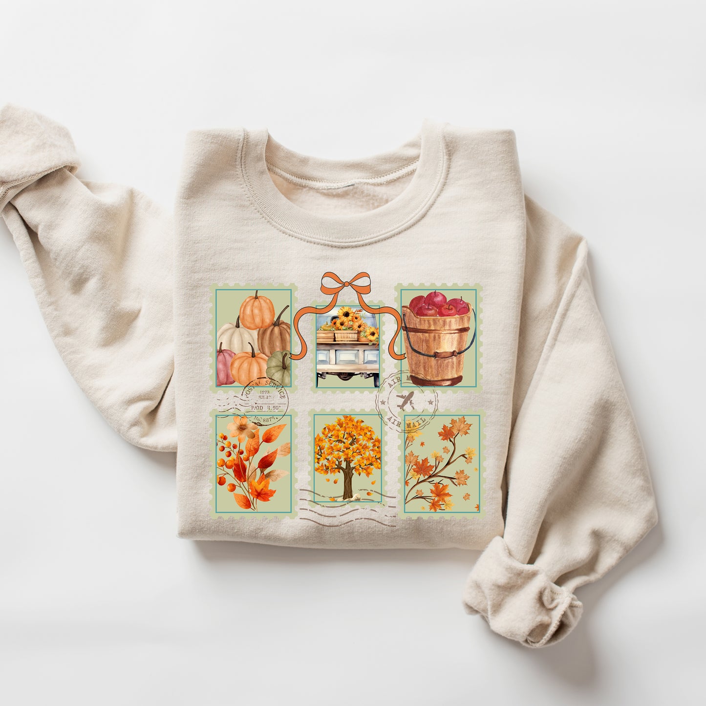 Beige sweatshirt with autumn-themed postage stamp design on a white background