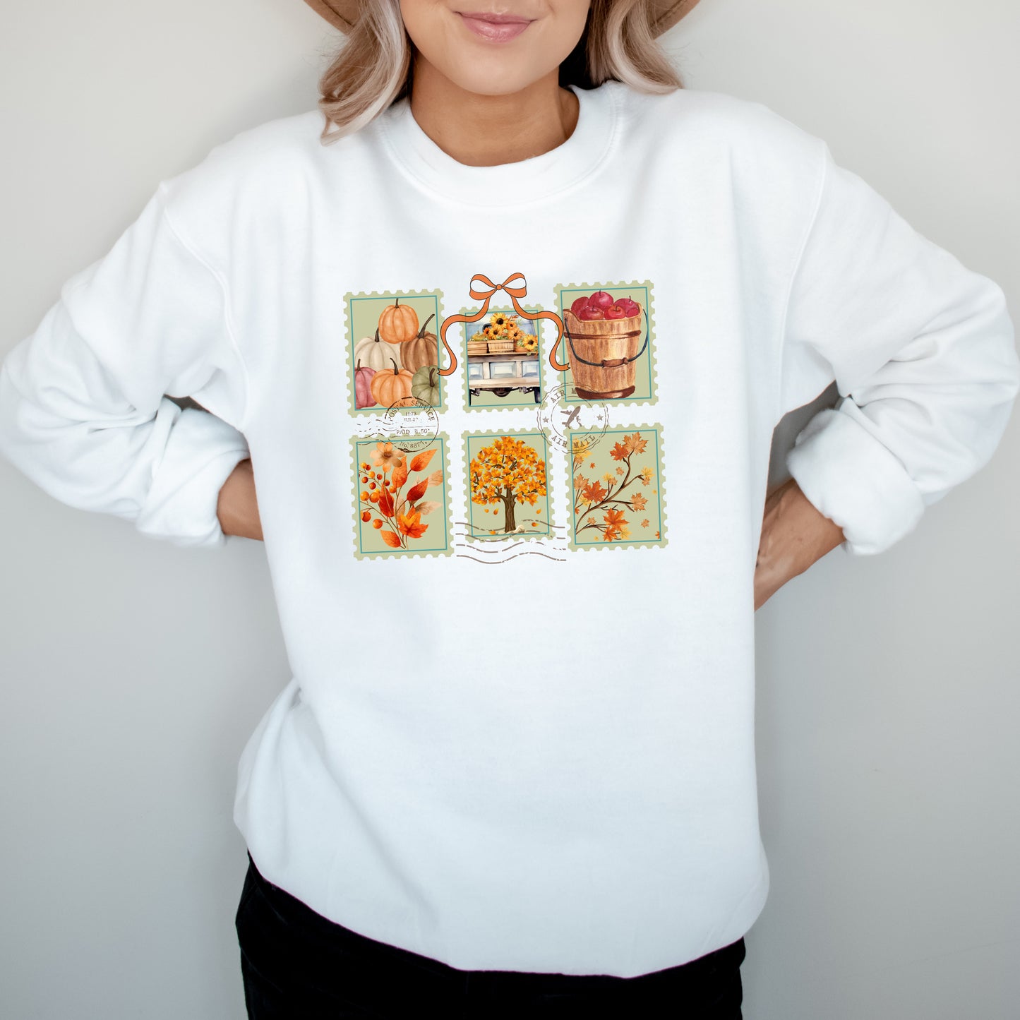White sweatshirt with autumn-themed postage stamp design on a plain background