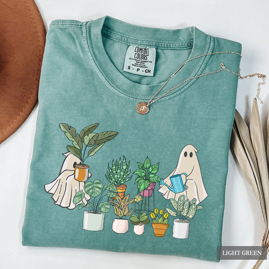 A light green comfort colors t-shirt with an image of ghosts tending to houseplants on it.