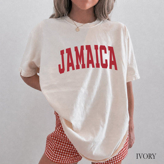 A woman wearing an oversized cream-colored t-shirt with 'JAMAICA' printed in red arched letters across the chest, paired with red and white gingham shorts. The image has a text overlay 'IVORY' in the bottom right corner.
