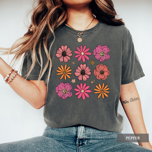 Person wearing a dark gray t-shirt with colorful floral designs on a plain background