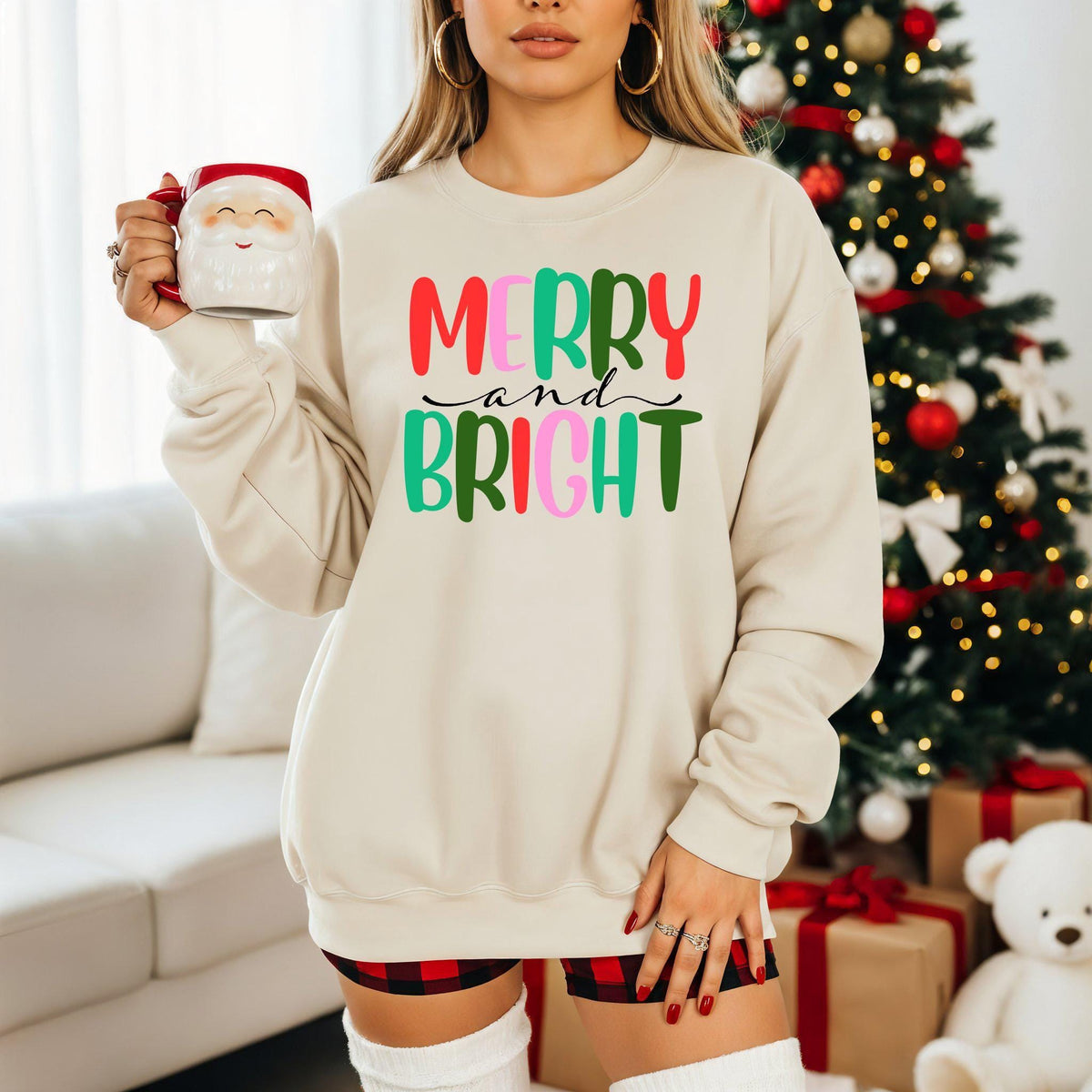 A maroon sweatshirt with Merry and Bright text shown folded on a wooden table.