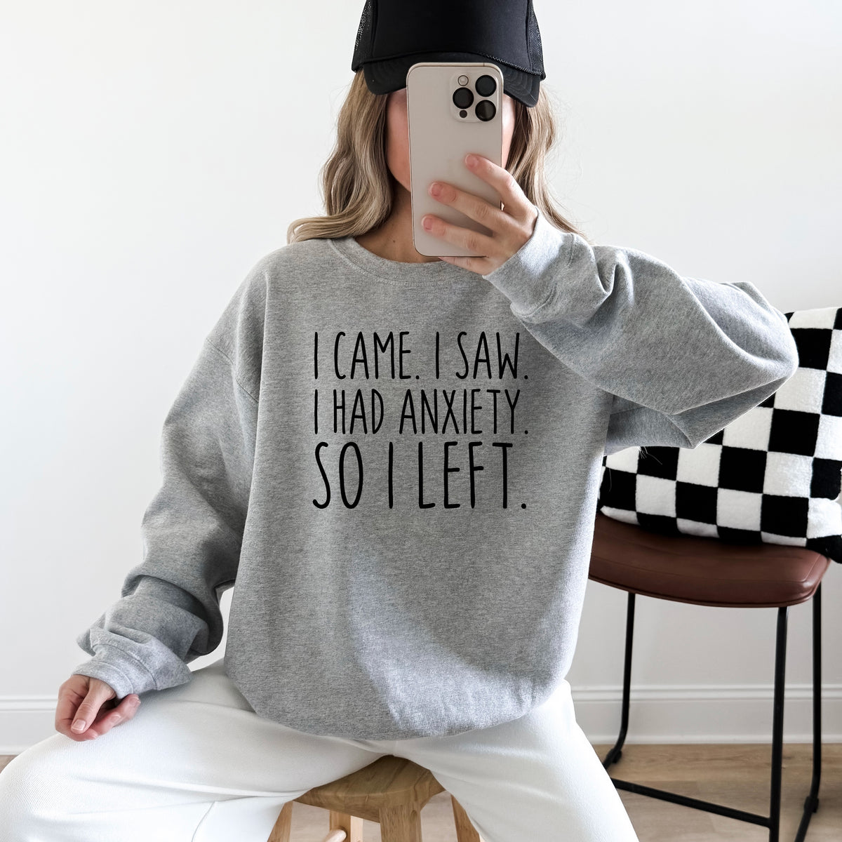A woman wearing a grey sweatshirt that says 'I Came I Saw I Had Anxiety So I Left.'