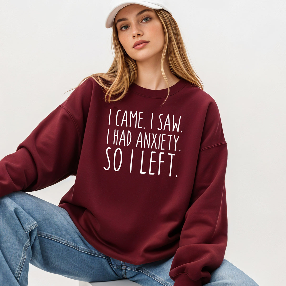 A woman wearing a maroon sweatshirt that says 'I Came I Saw I Had Anxiety So I Left.'