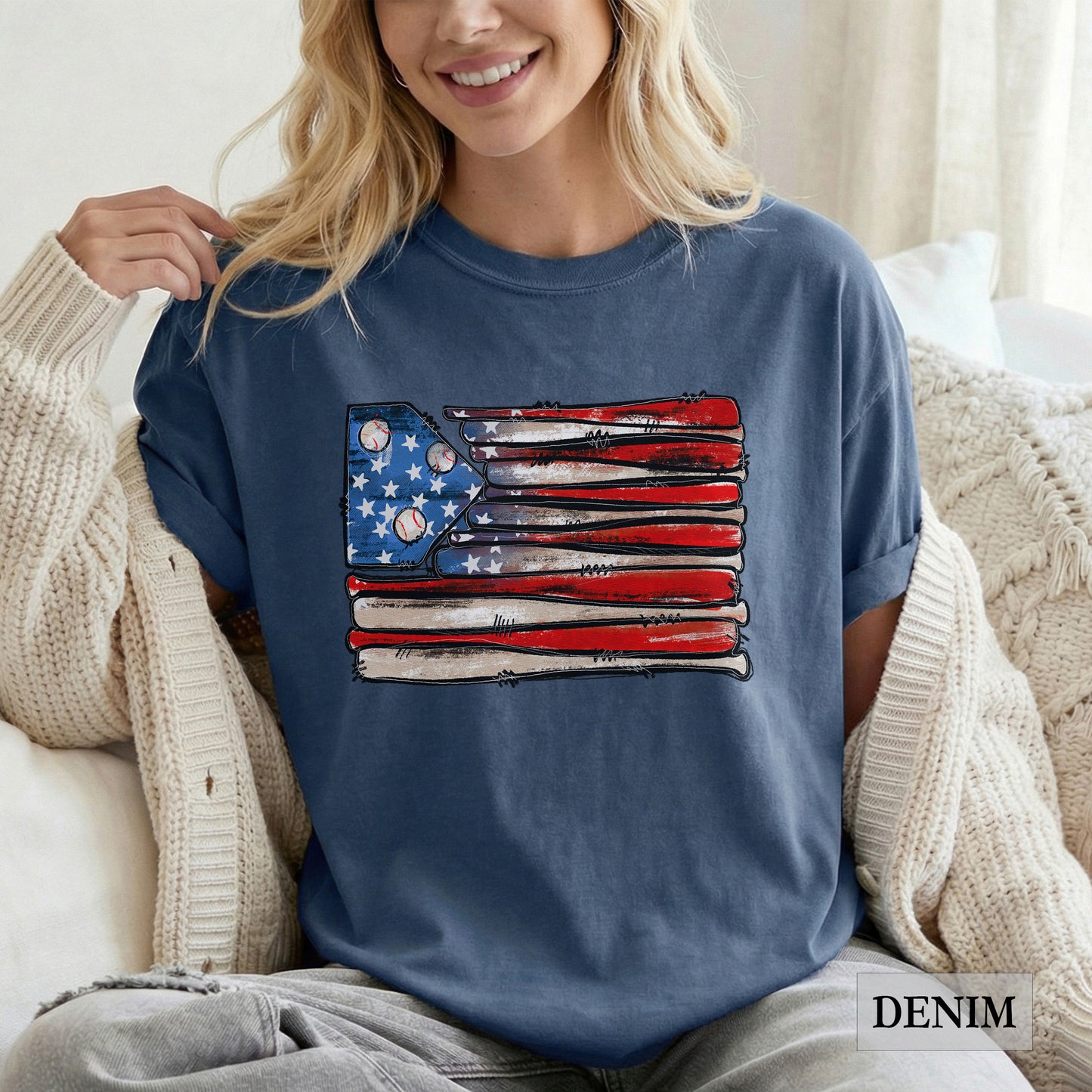 Woman wearing a blue t-shirt with an American flag design, sitting on a couch.