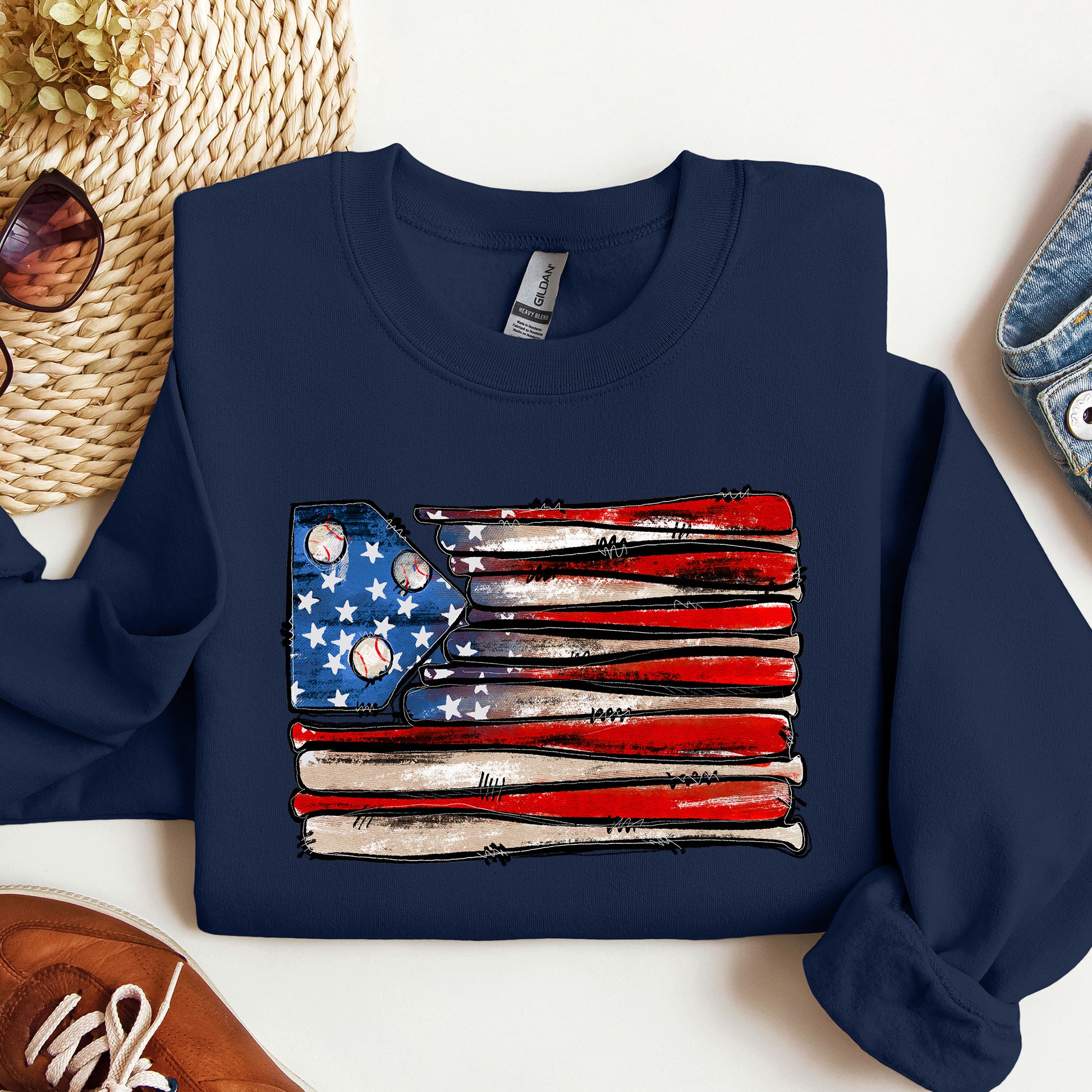 Navy blue sweatshirt with American flag design featuring baseball bats and balls on a white surface.
