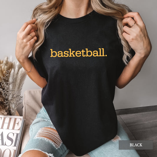 A woman wearing a black comfort colors t-shirt with basketball on it.