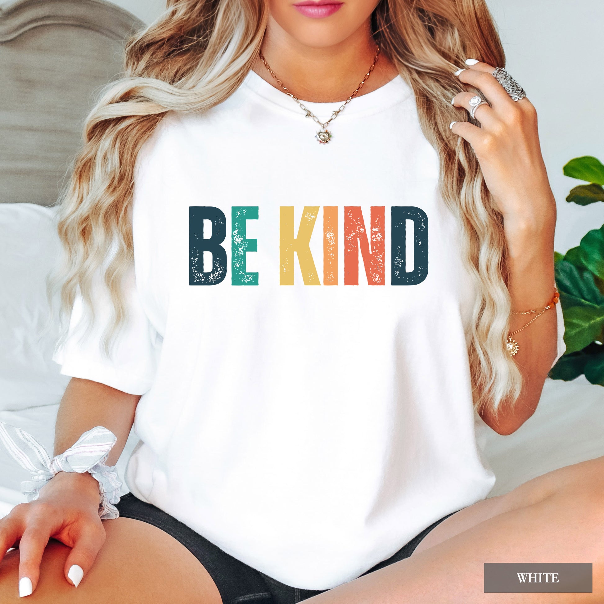 Person wearing a white t-shirt with 'BE KIND' text in colorful letters.