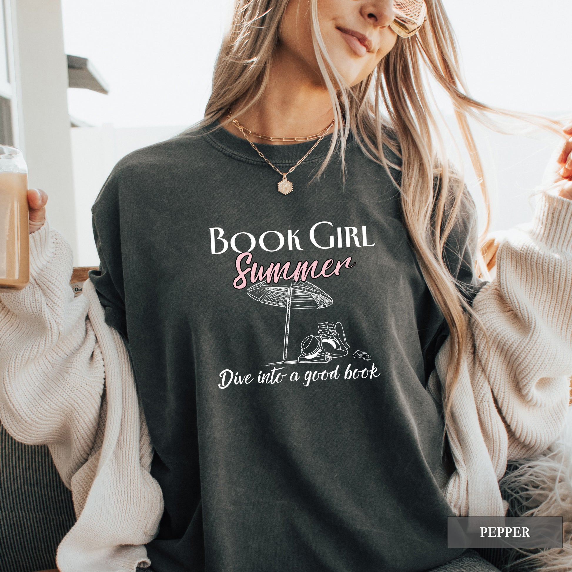 Person wearing a black sweatshirt with 'Book Girl Summer' text and graphics.