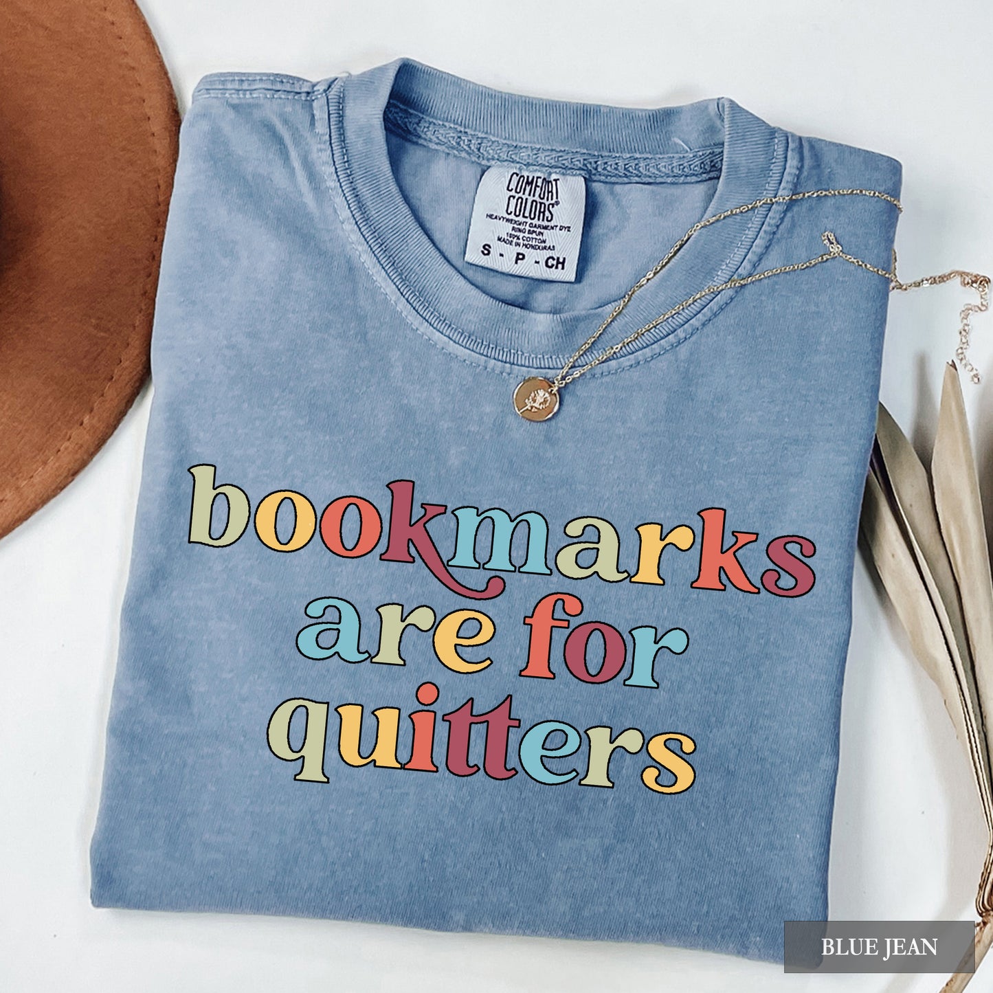 Blue denim shirt with colorful text 'bookmarks are for quitters' on a white background