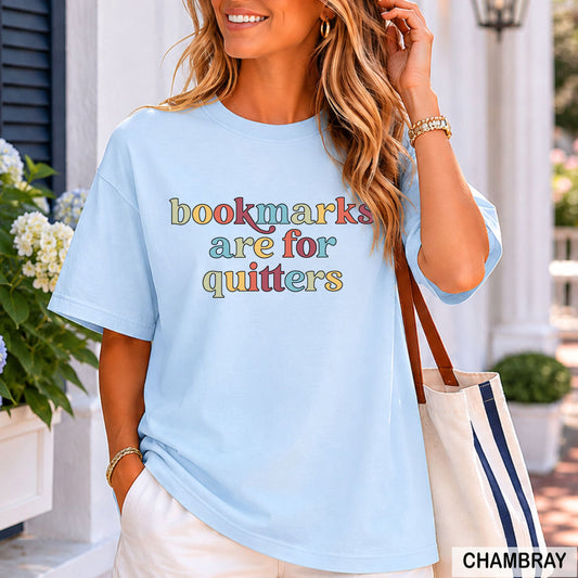 Woman wearing a light blue t-shirt with colorful text, standing outdoors.
