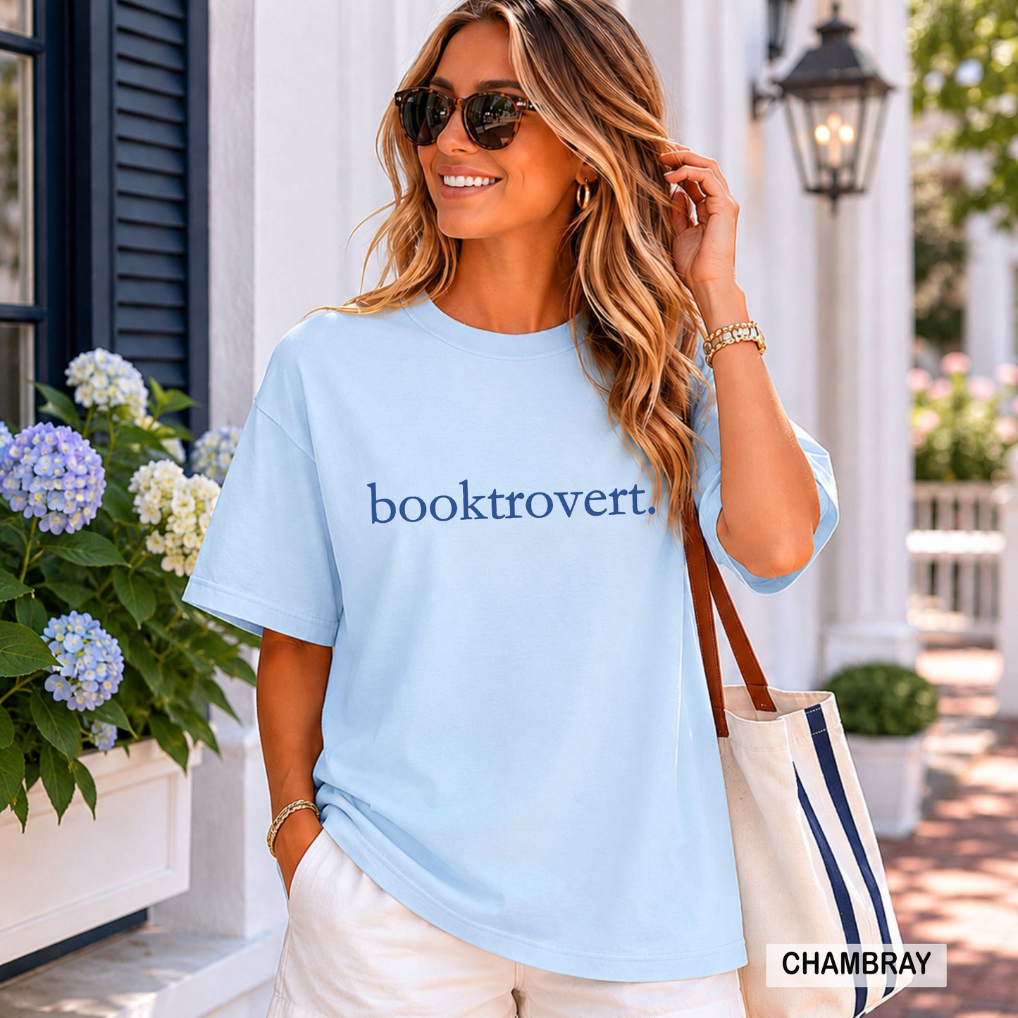 Woman wearing a chambray comfort colors shirt with "booktrovert" on the front in minimalist typewriter style font.