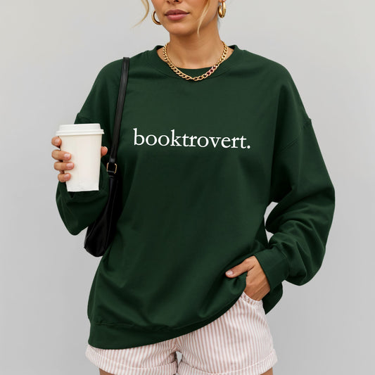 Woman wearing a forest green Gildan sweatshirt with 'booktrovert' on it in minimalist typewriter style font.