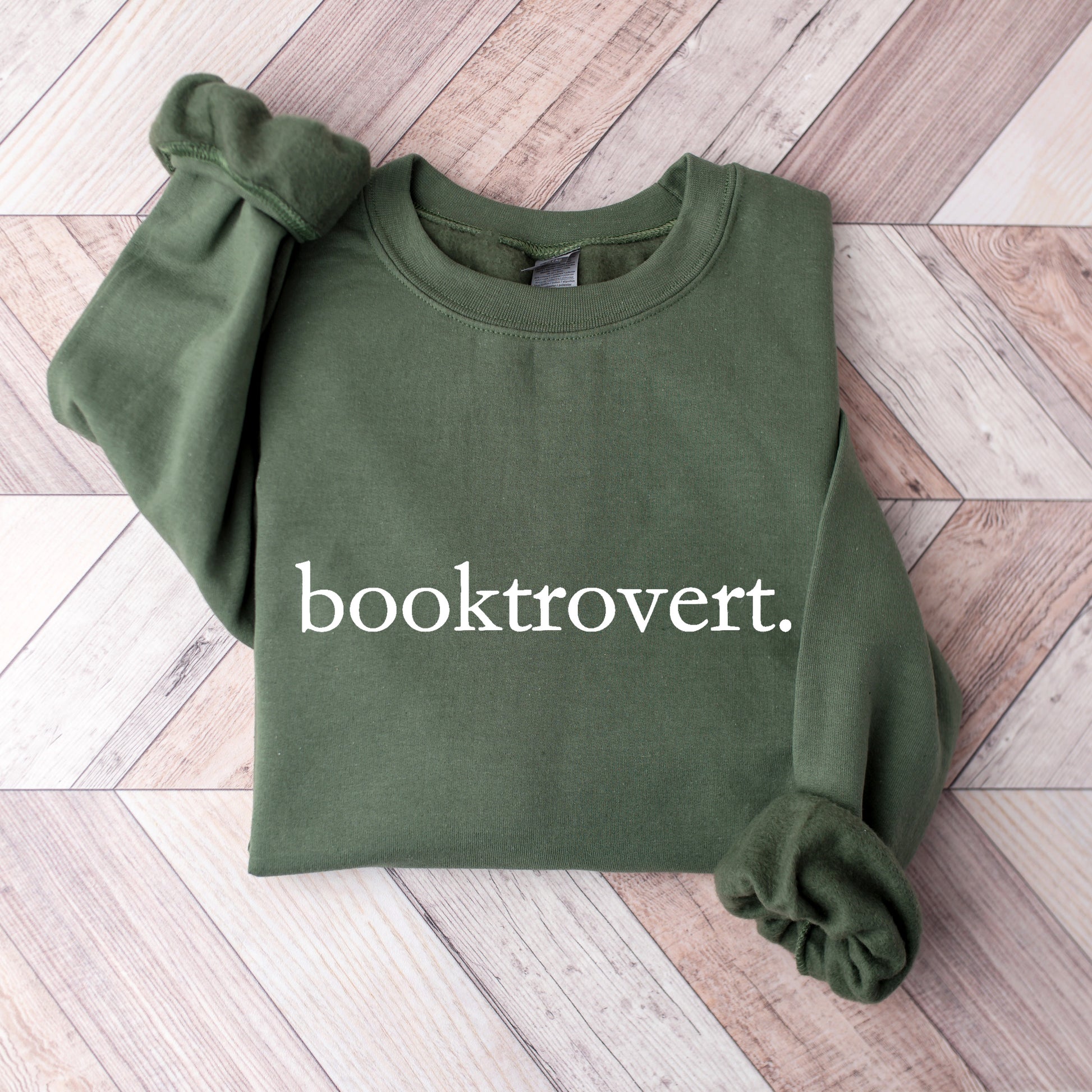 A Military Green Gildan sweatshirt with 'booktrovert' on it in minimalist typewriter style font.