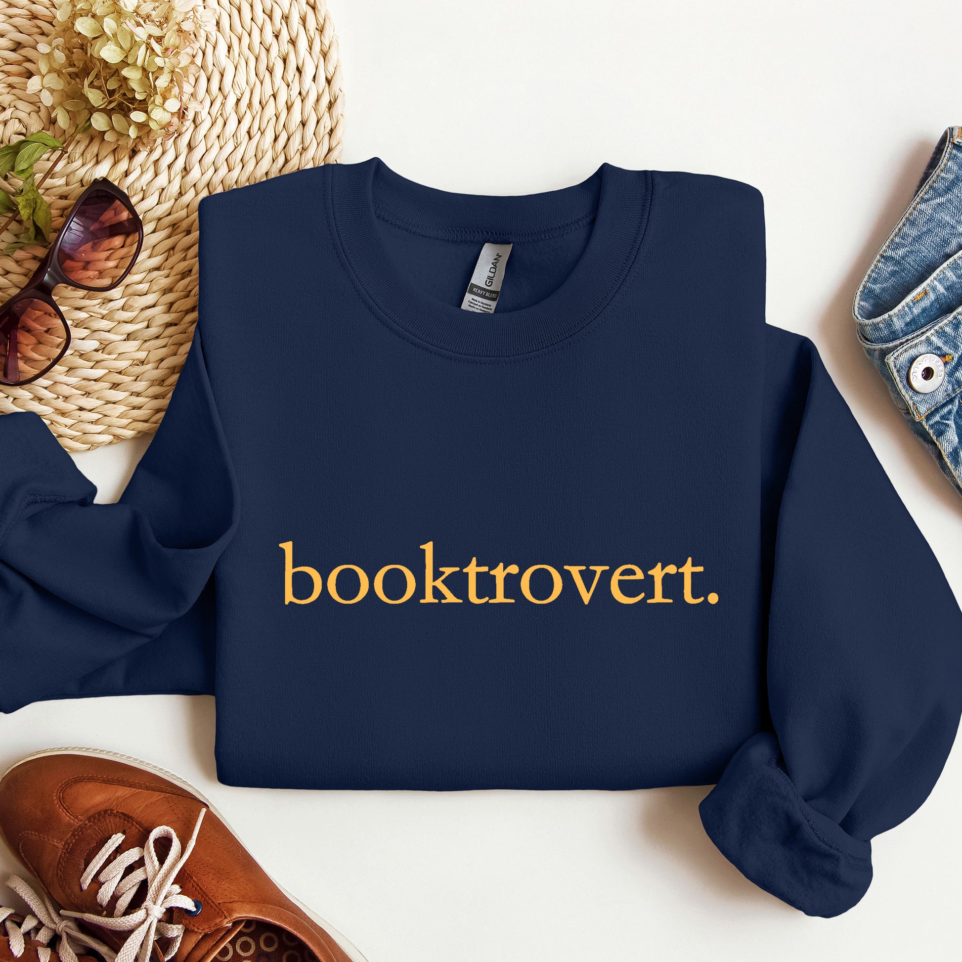 A Navy blue Gildan sweatshirt with 'booktrovert' on it in minimalist typewriter style font.