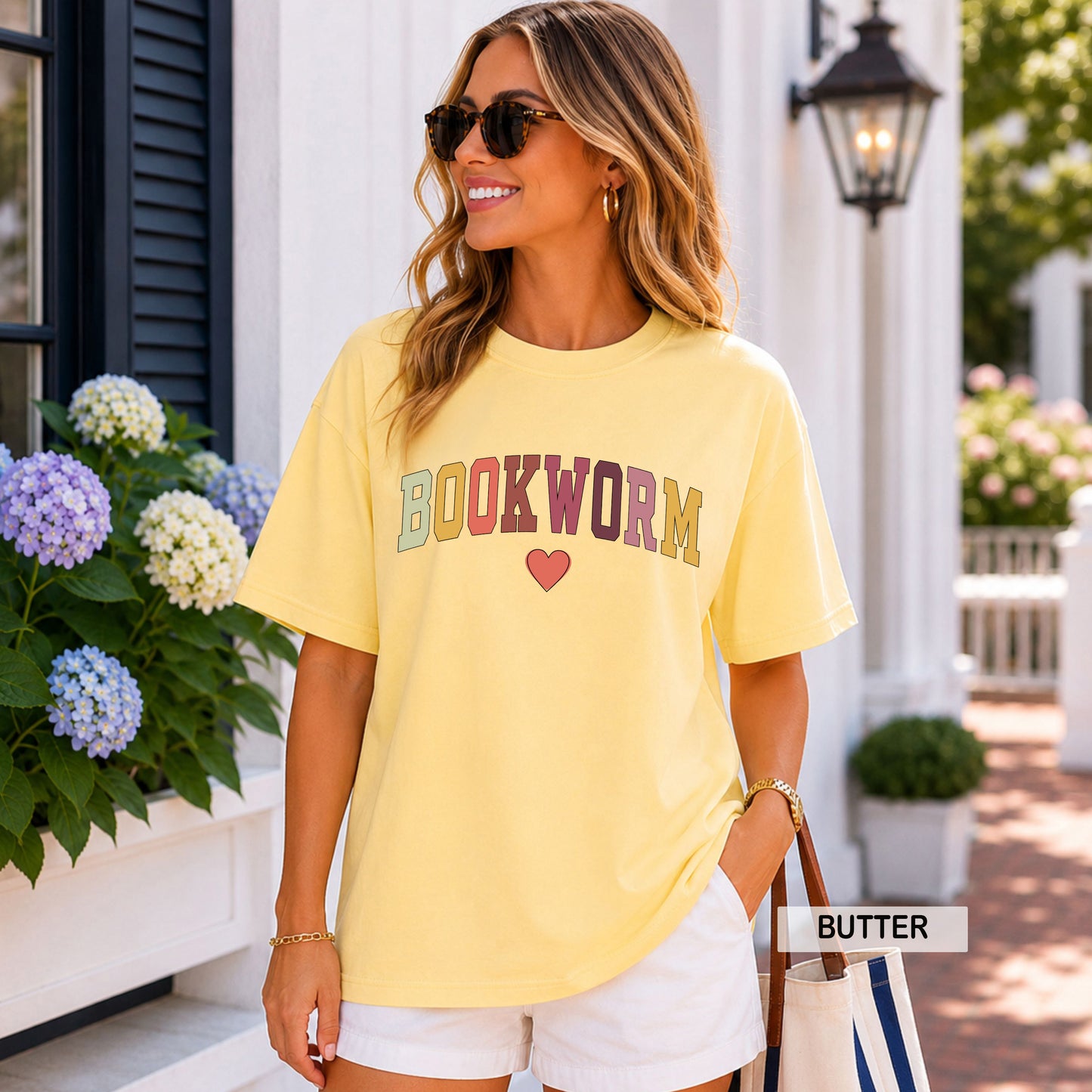 Woman wearing a yellow 'BOOKWORM' t-shirt with a heart, standing outdoors.