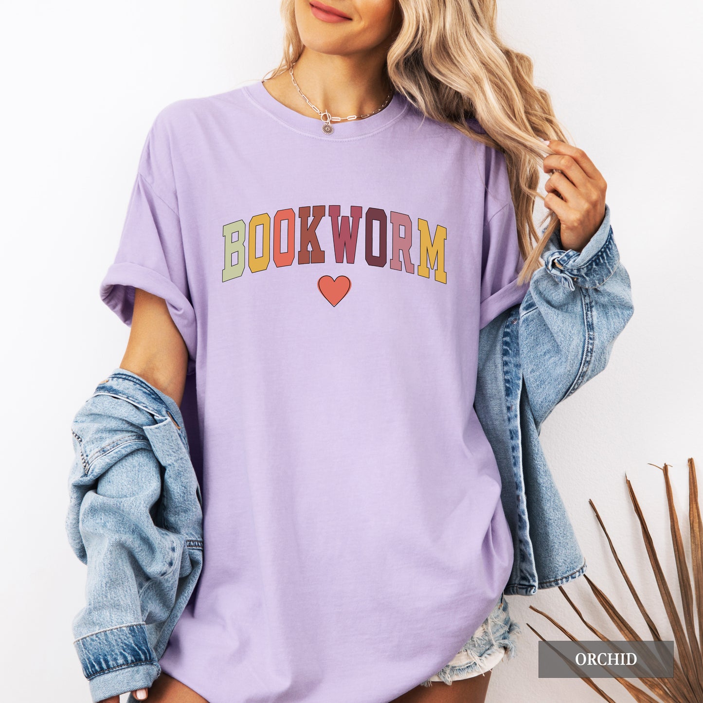 Person wearing a purple 'BOOKWORM' t-shirt with a heart symbol on a white background