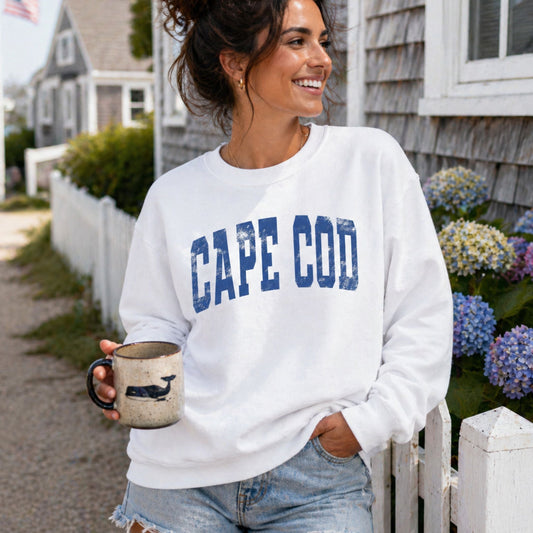 Woman wearing a 'Cape Cod' sweatshirt holding a mug outdoors.