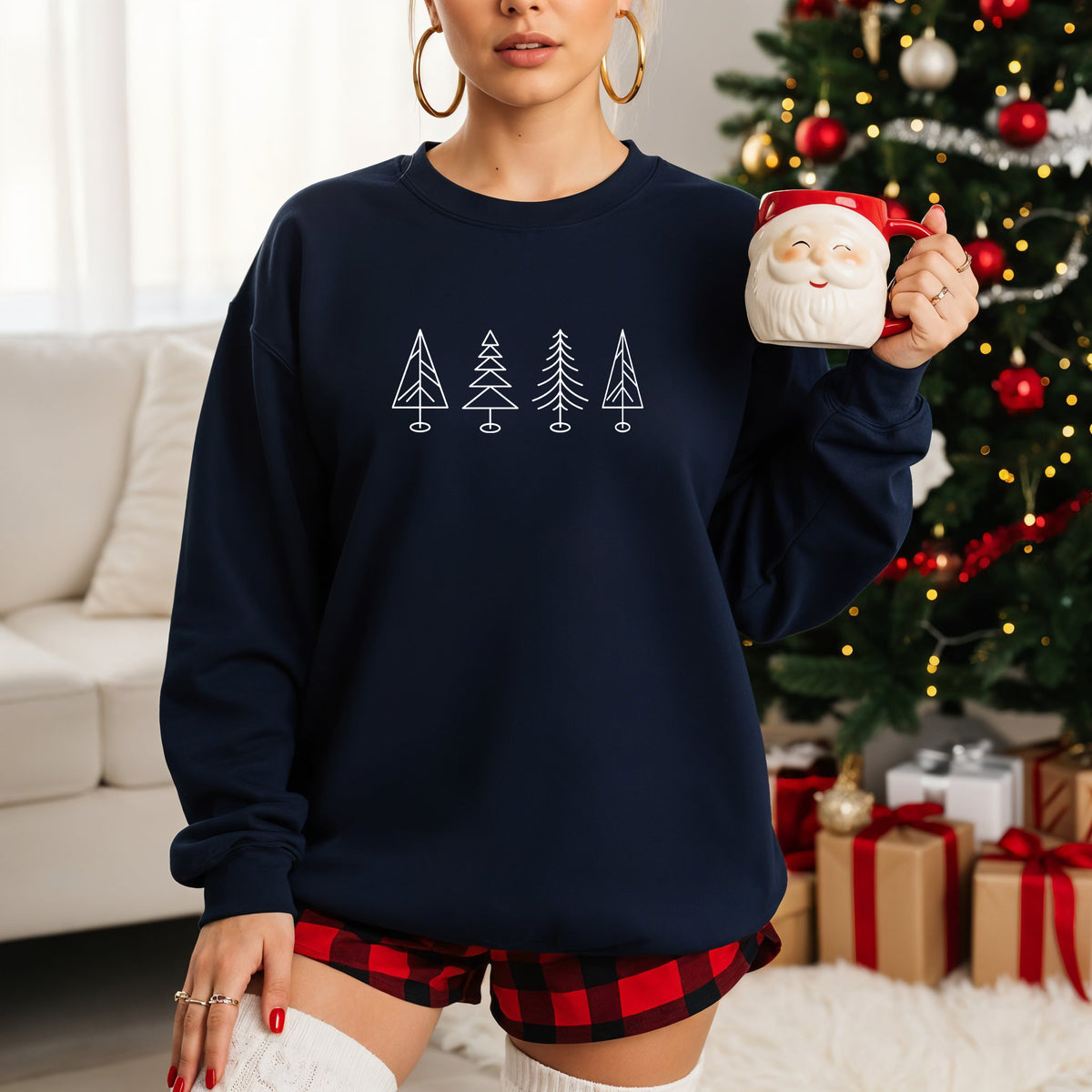 A woman wearing a navy Gildan crewneck sweatshirt with 4 line drawn Christmas trees on it.