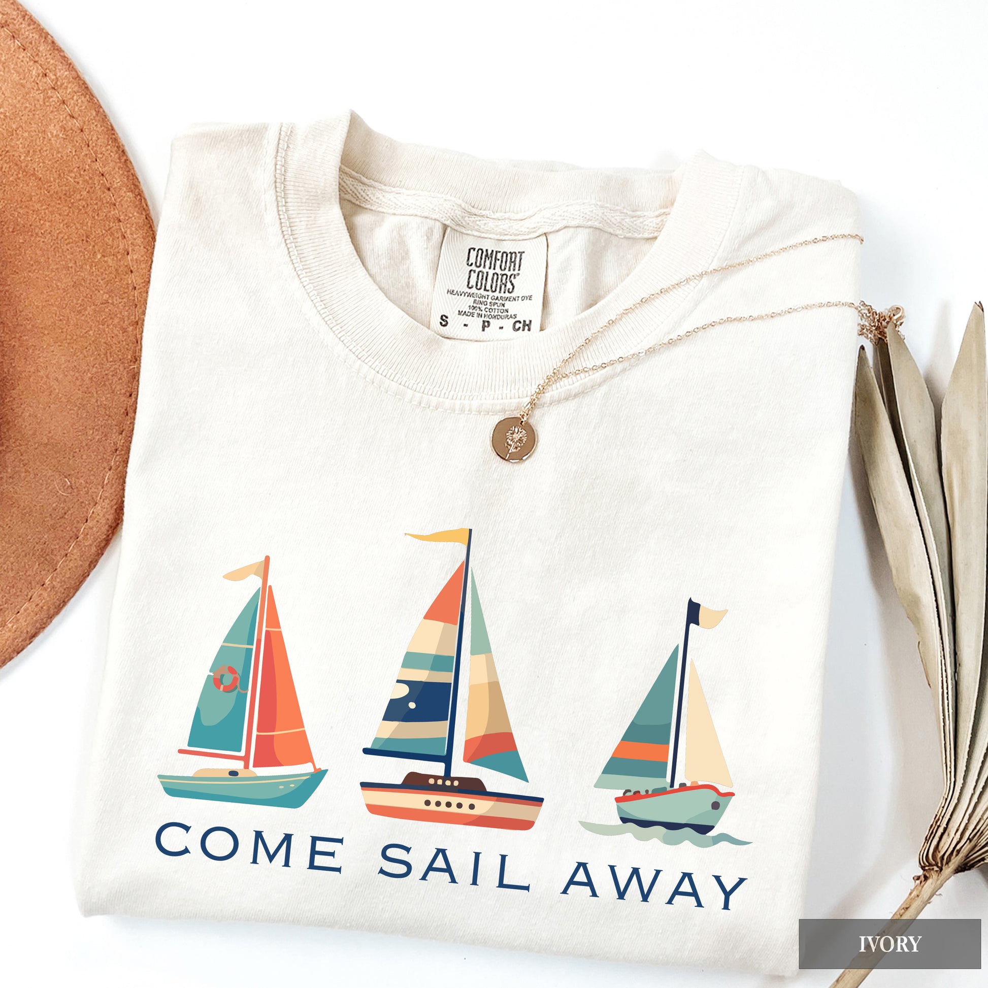 White shirt with sailboat design and 'Come Sail Away' text on a white background