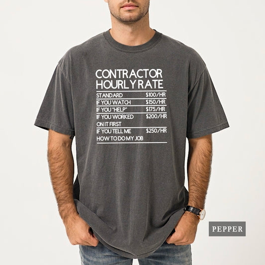 A man wearing a dark gray graphic t-shirt with white text that reads 'CONTRACTOR HOURLY RATE' followed by a humorous pay table. The t-shirt is labeled 'PEPPER' in a small gray box in the bottom right corner.