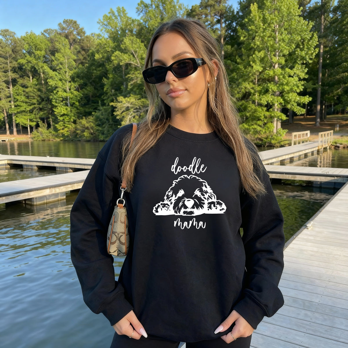 A woman wearing a black sweatshirt with 'doodle mama' and a picture of a goldendoodle on it.