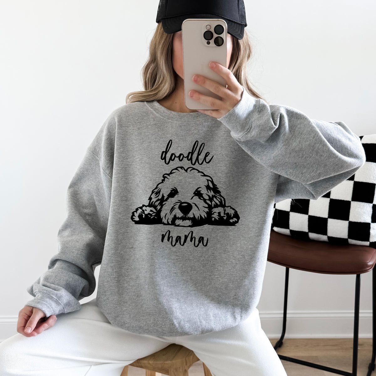 A woman wearing a grey sweatshirt with 'doodle mama' and a picture of a goldendoodle on it.