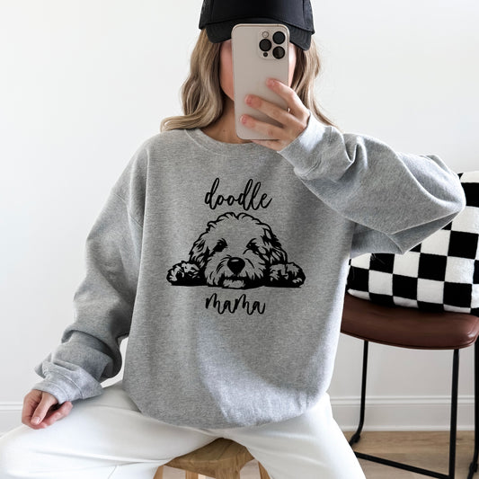 A woman wearing a grey sweatshirt with 'doodle mama' and a picture of a goldendoodle on it.