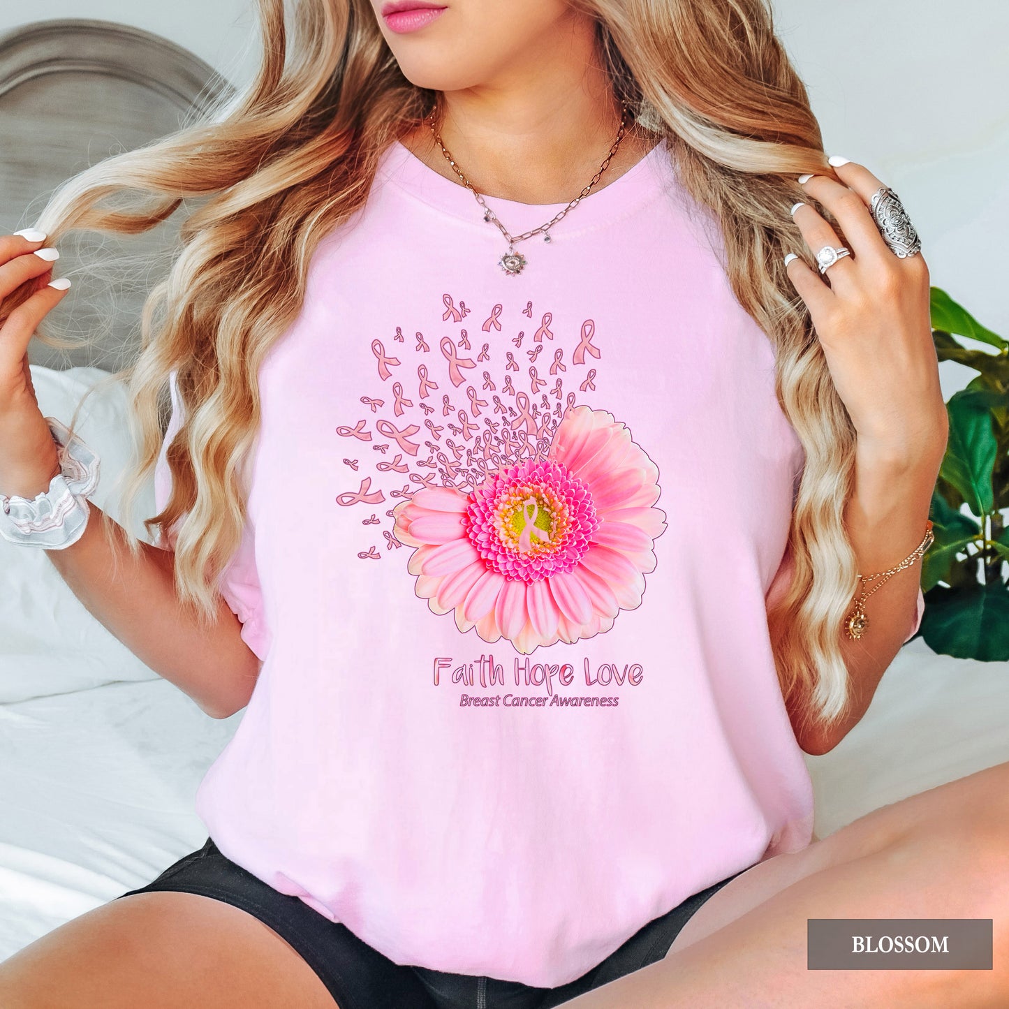Woman wearing a pink t-shirt with a floral design and 'Faith Hope Love' text, sitting on a couch.