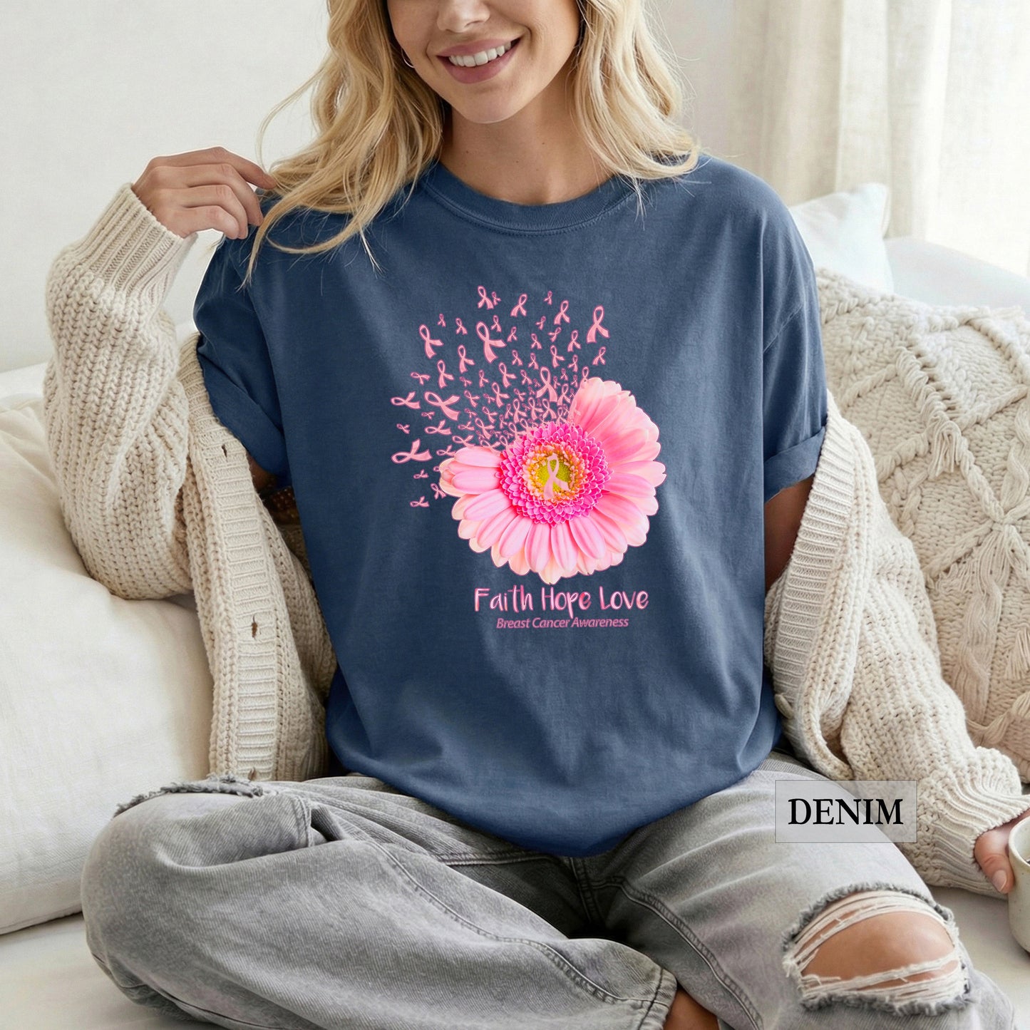 Woman wearing a blue sweatshirt with a pink flower design and 'Faith Hope Love' text, sitting on a couch.