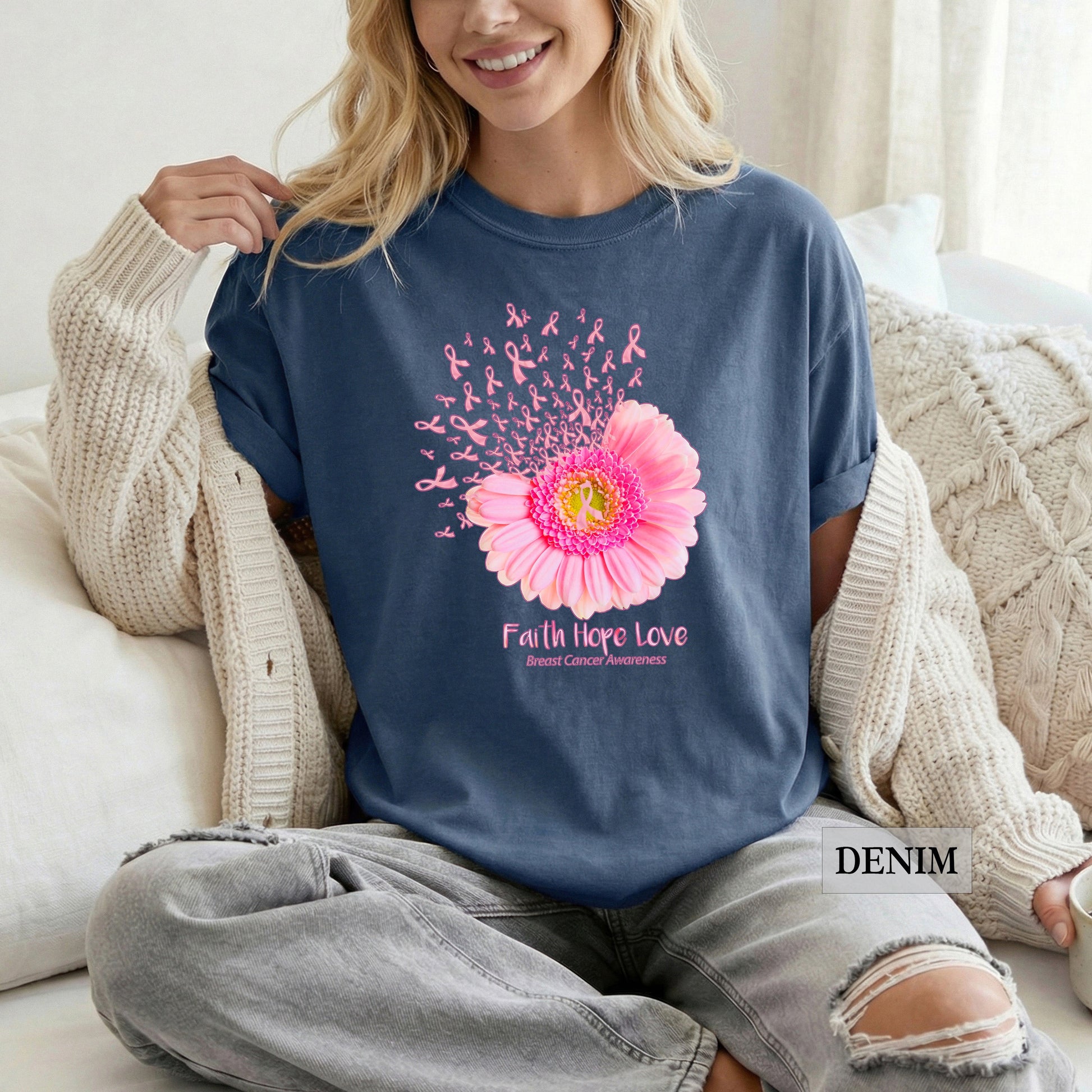 Woman wearing a blue sweatshirt with a pink flower design and 'Faith Hope Love' text, sitting on a couch.