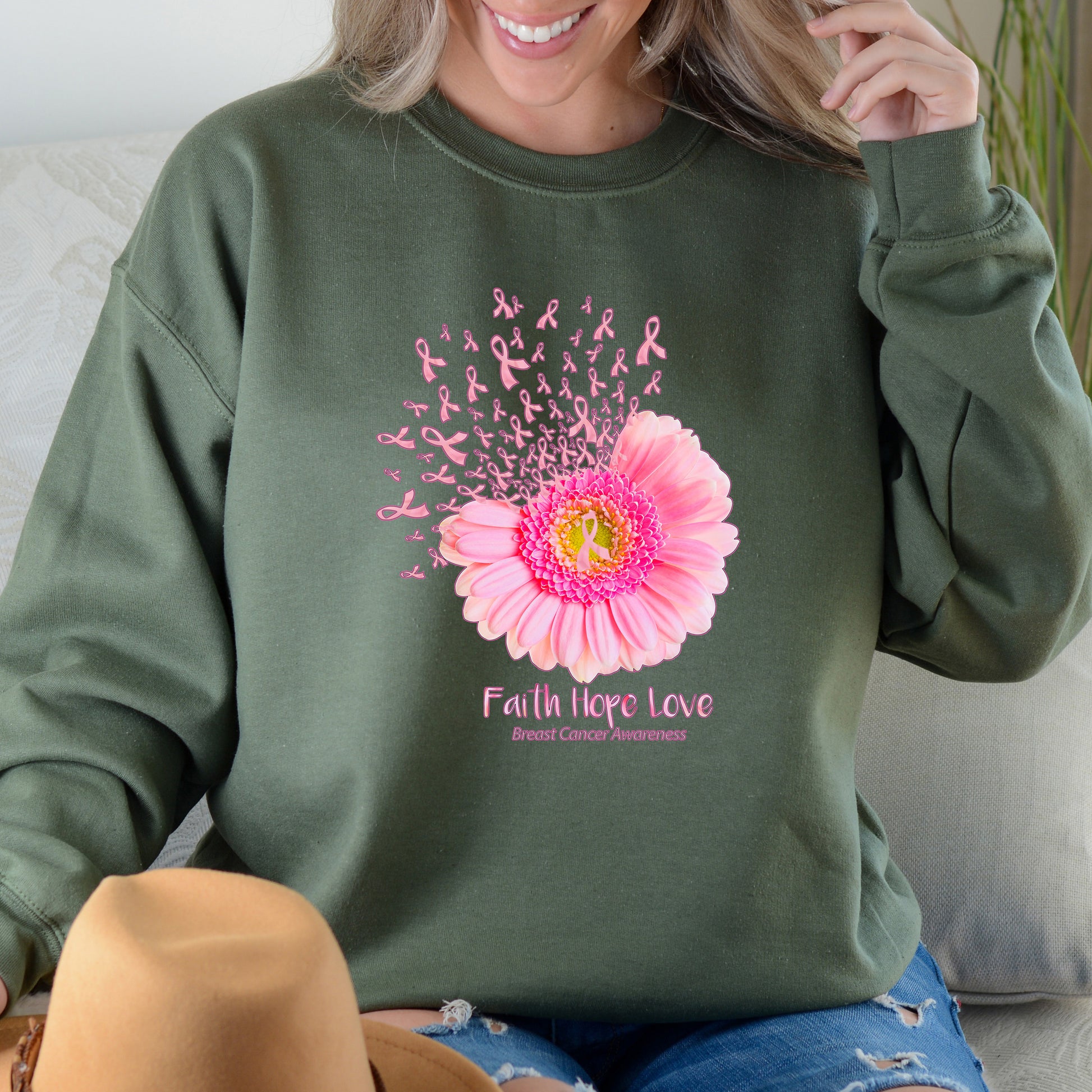 Person wearing a green sweatshirt with a pink flower and breast cancer awareness design.
