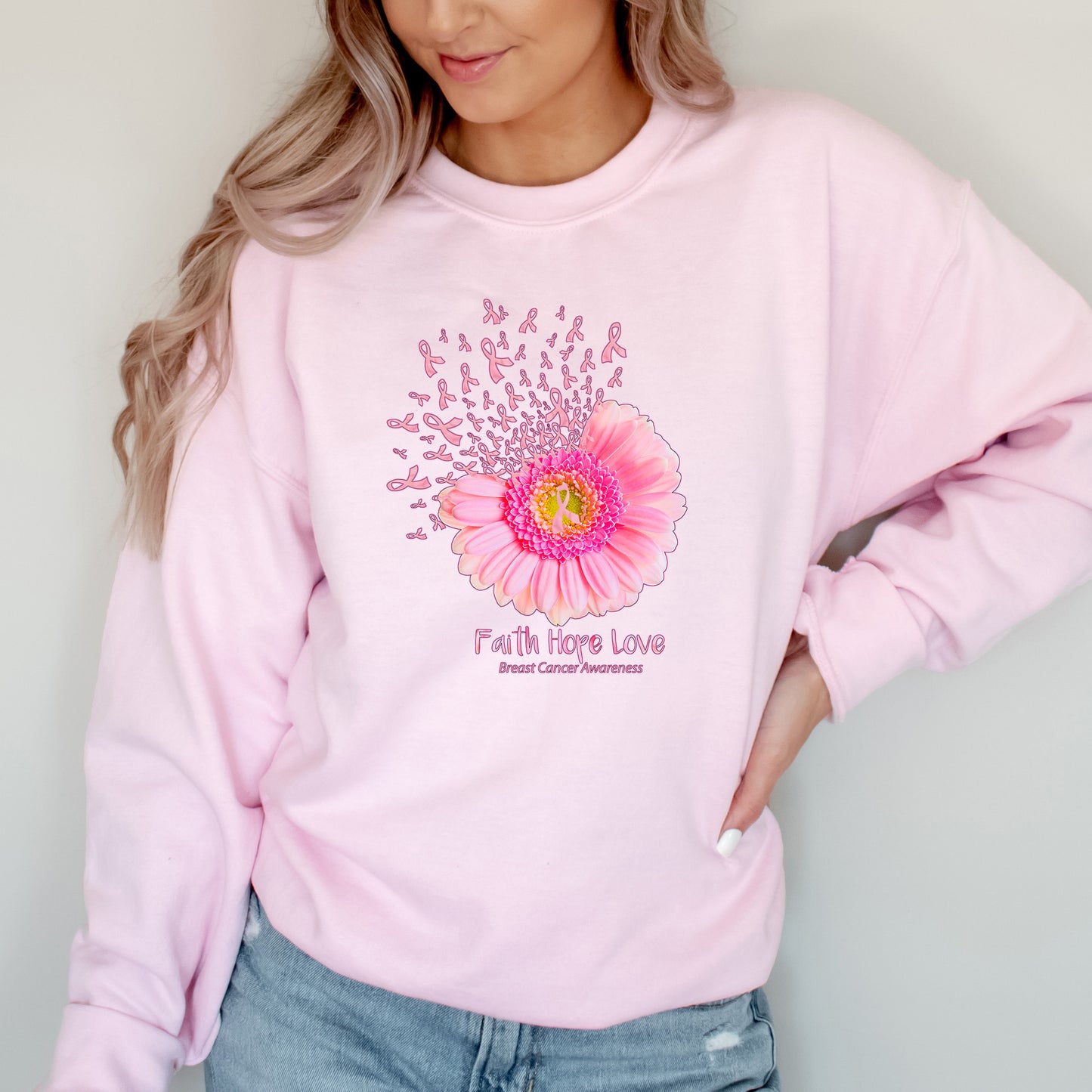 Person wearing a pink sweatshirt with a floral design and 'Faith Hope Love' text on a plain background