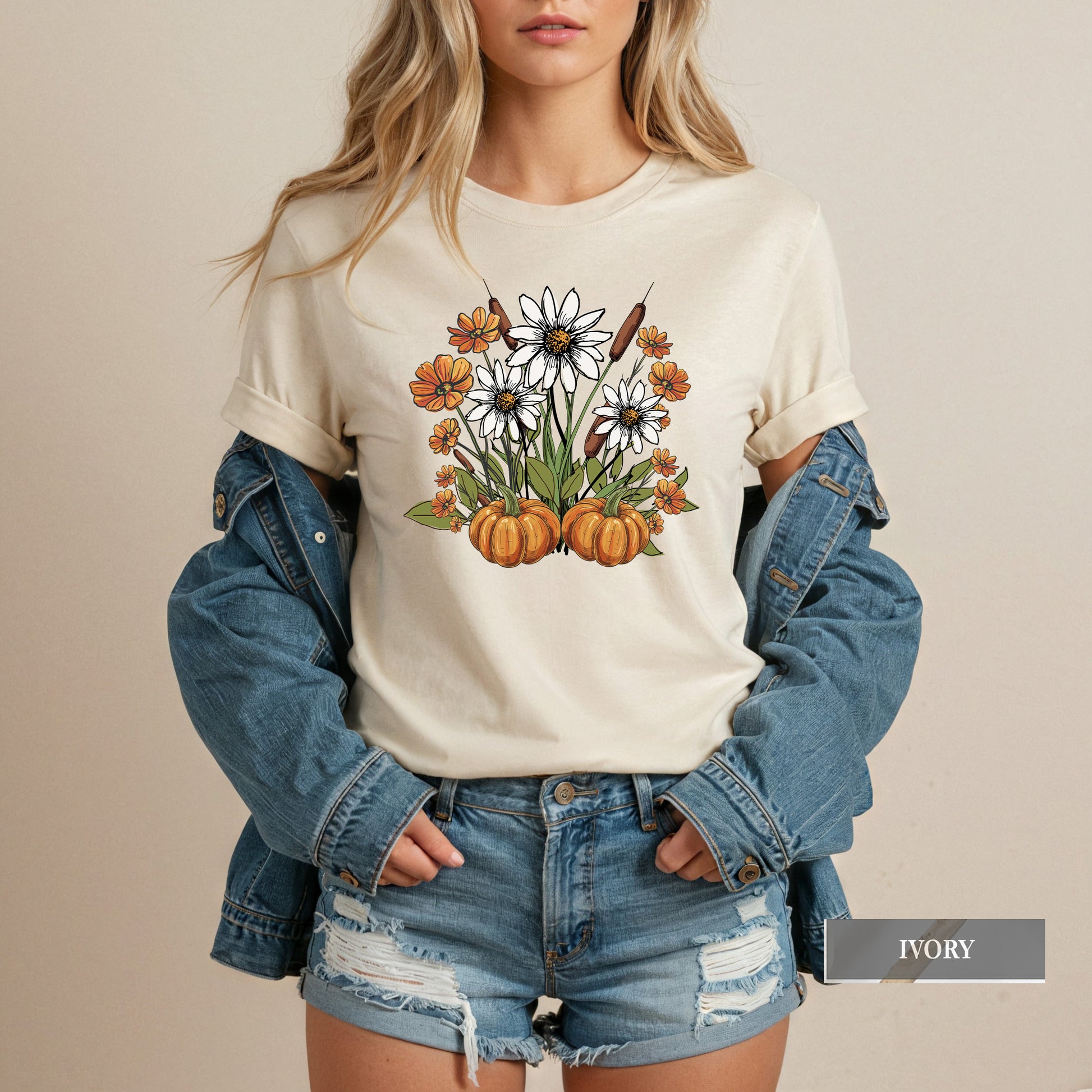 Person wearing a white t-shirt with a floral and pumpkin design, paired with a denim jacket and shorts.