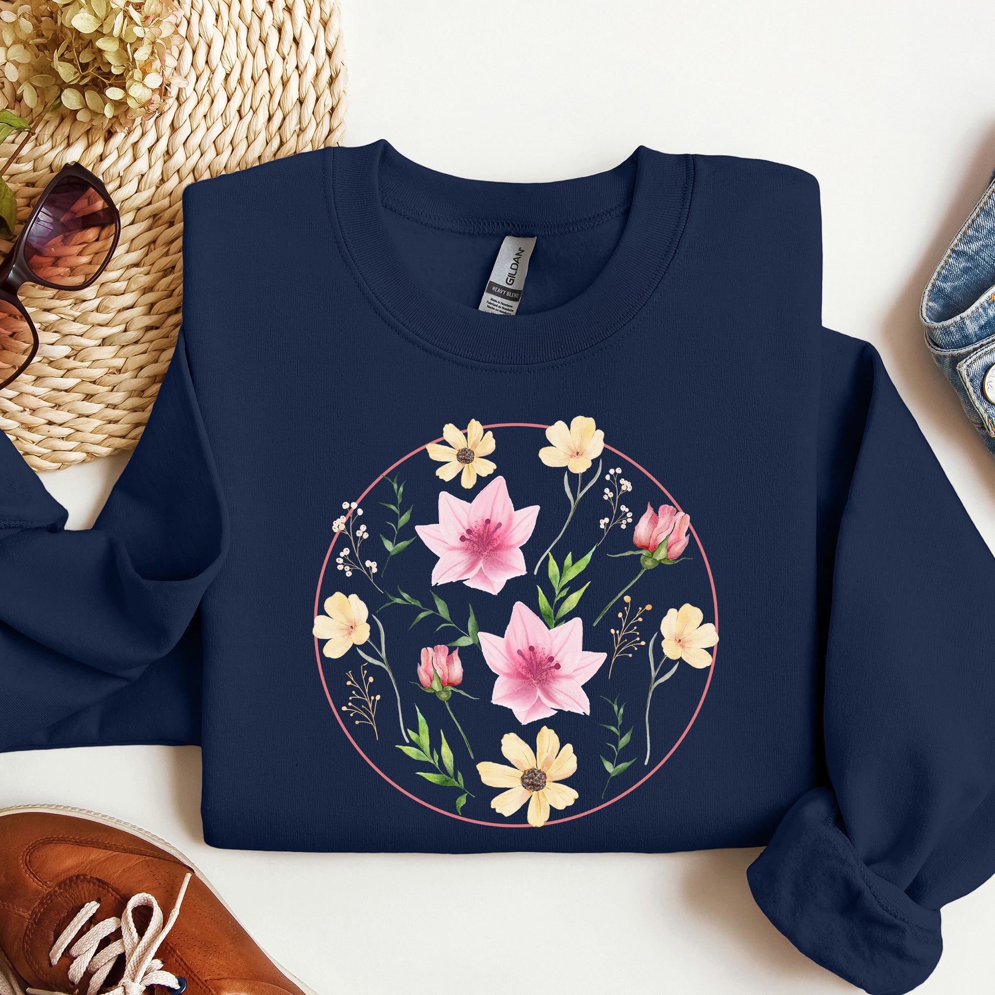 Navy blue sweatshirt with floral design on a white surface with accessories.