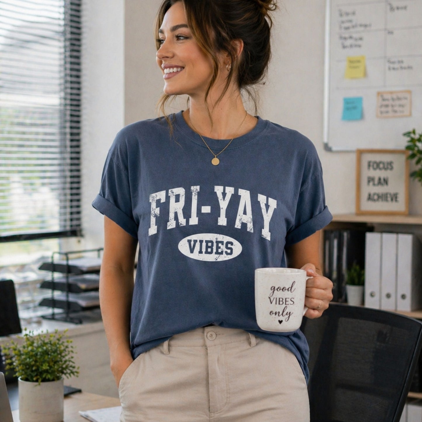 Woman in an office setting wearing a 'FRI-YAY VIBES' t-shirt and holding a mug.