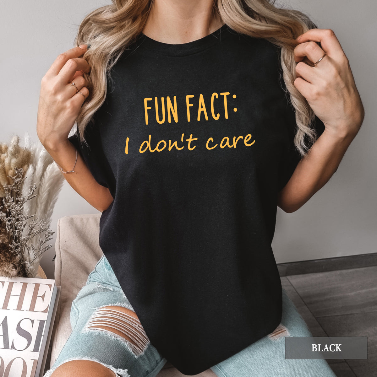 A woman wearing a black comfort colors shirt that says 'Fun Fact: I don't care' on it.