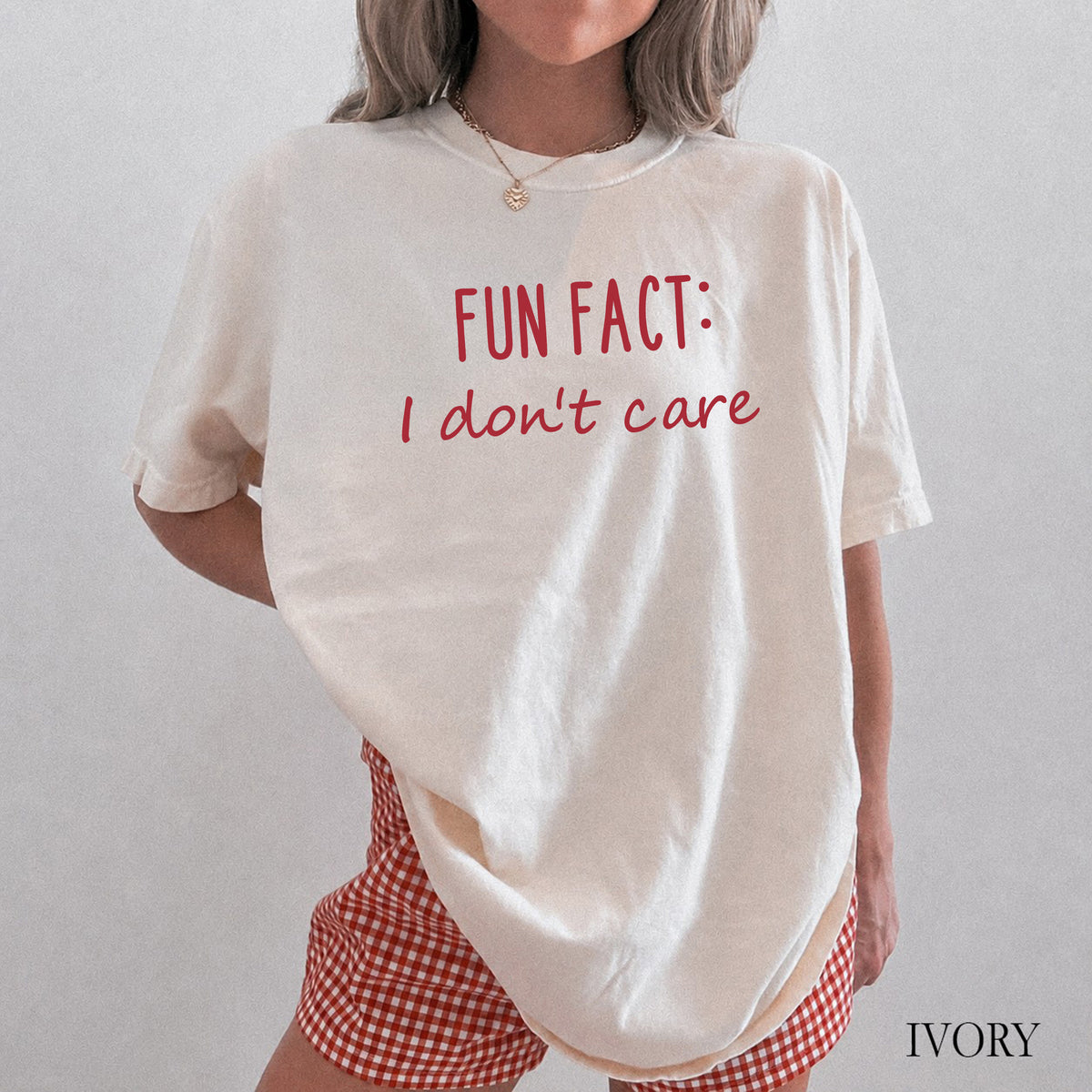 A woman wearing an ivory comfort colors shirt that says 'Fun Fact: I don't care' on it.
