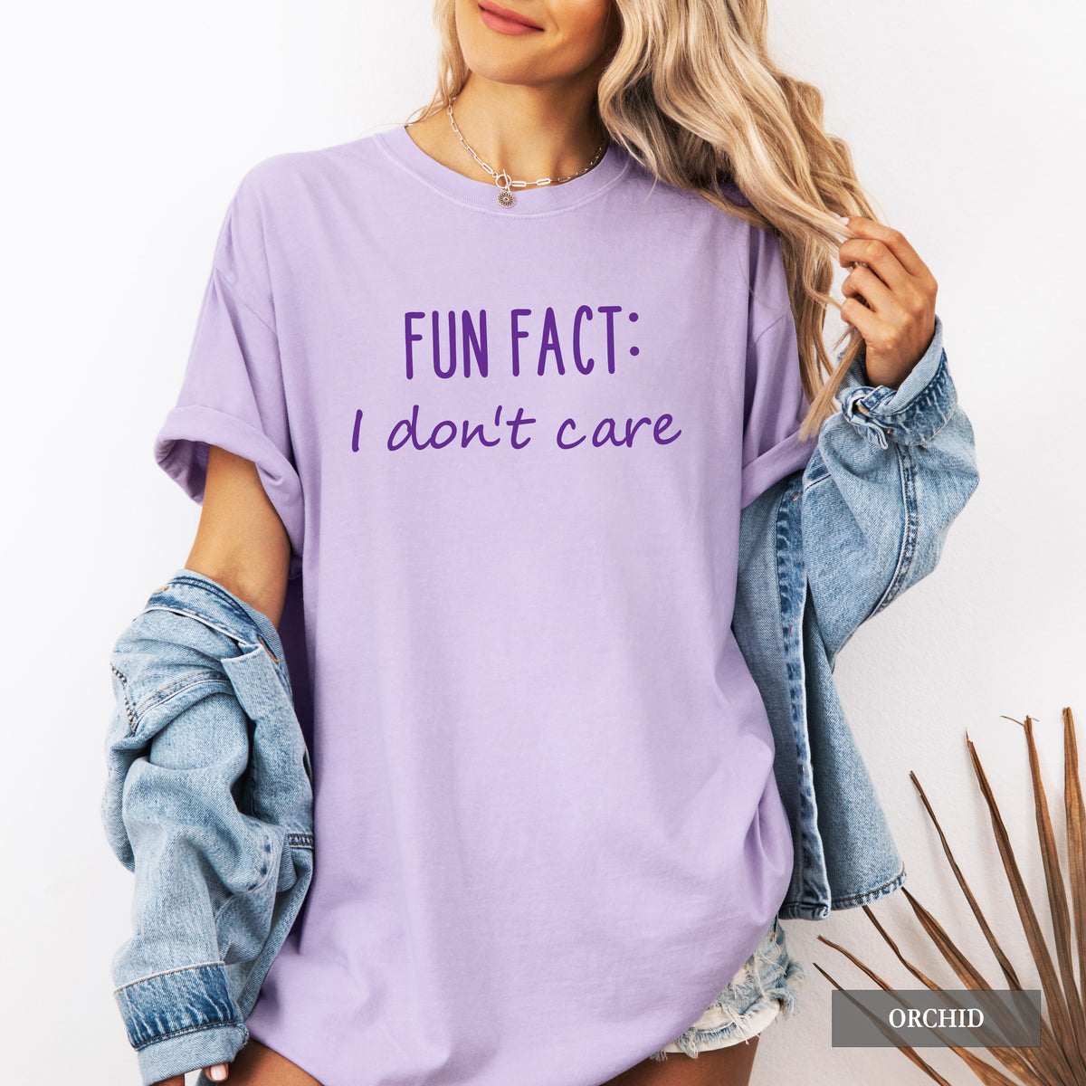 A woman wearing an orchid comfort colors shirt that says 'Fun Fact: I don't care' on it.
