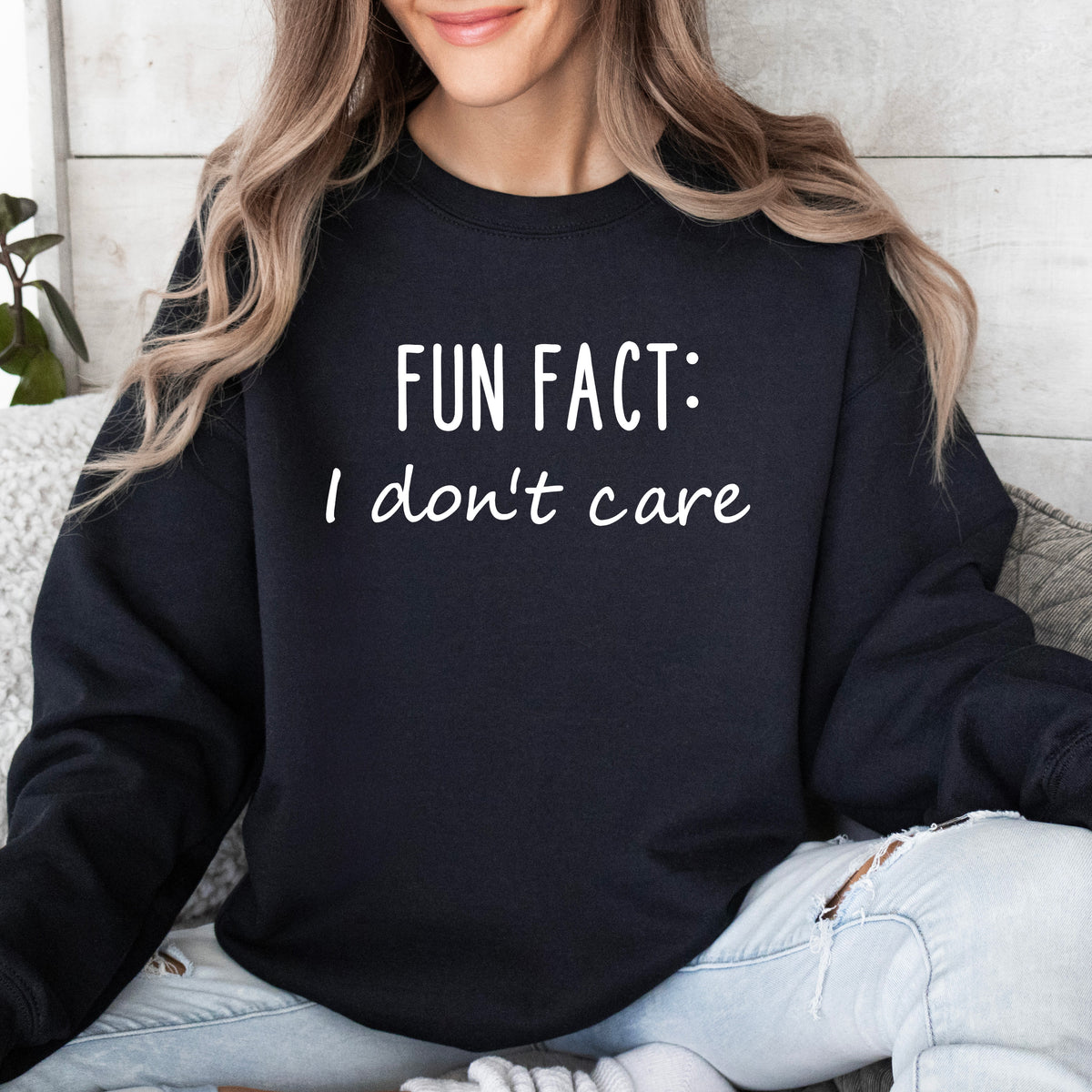 A woman wearing a black sweatshirt that says 'Fun Fact: I don't care' on it.