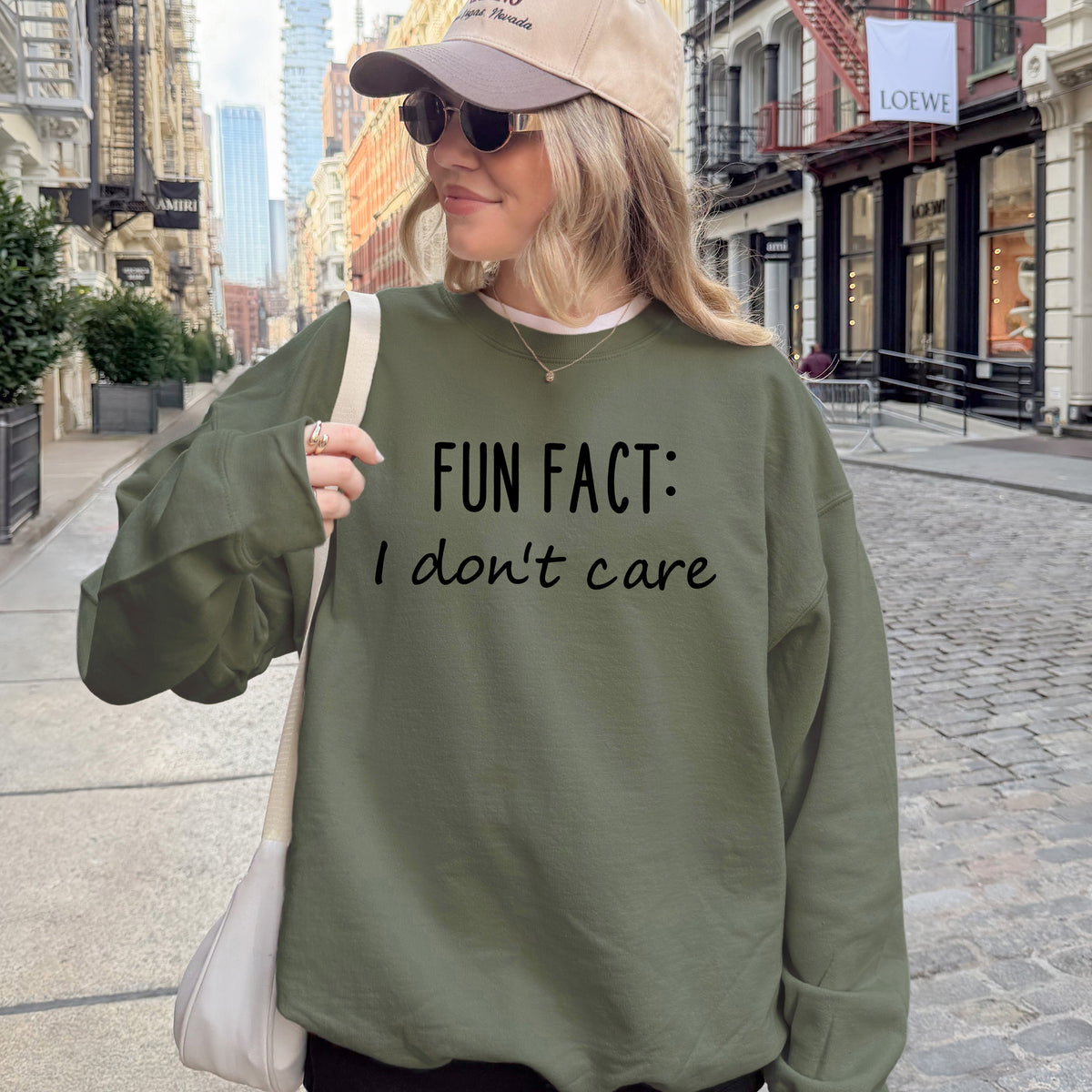 A woman wearing a military green sweatshirt that says 'Fun Fact: I don't care' on it.