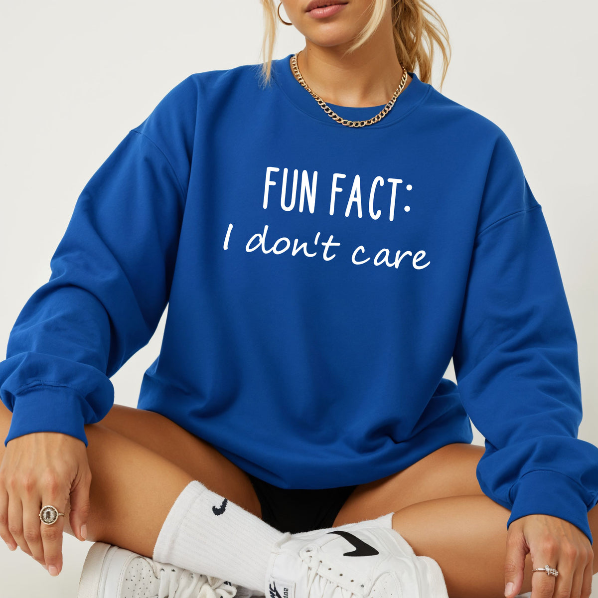 A woman wearing a royal blue sweatshirt that says 'Fun Fact: I don't care' on it.
