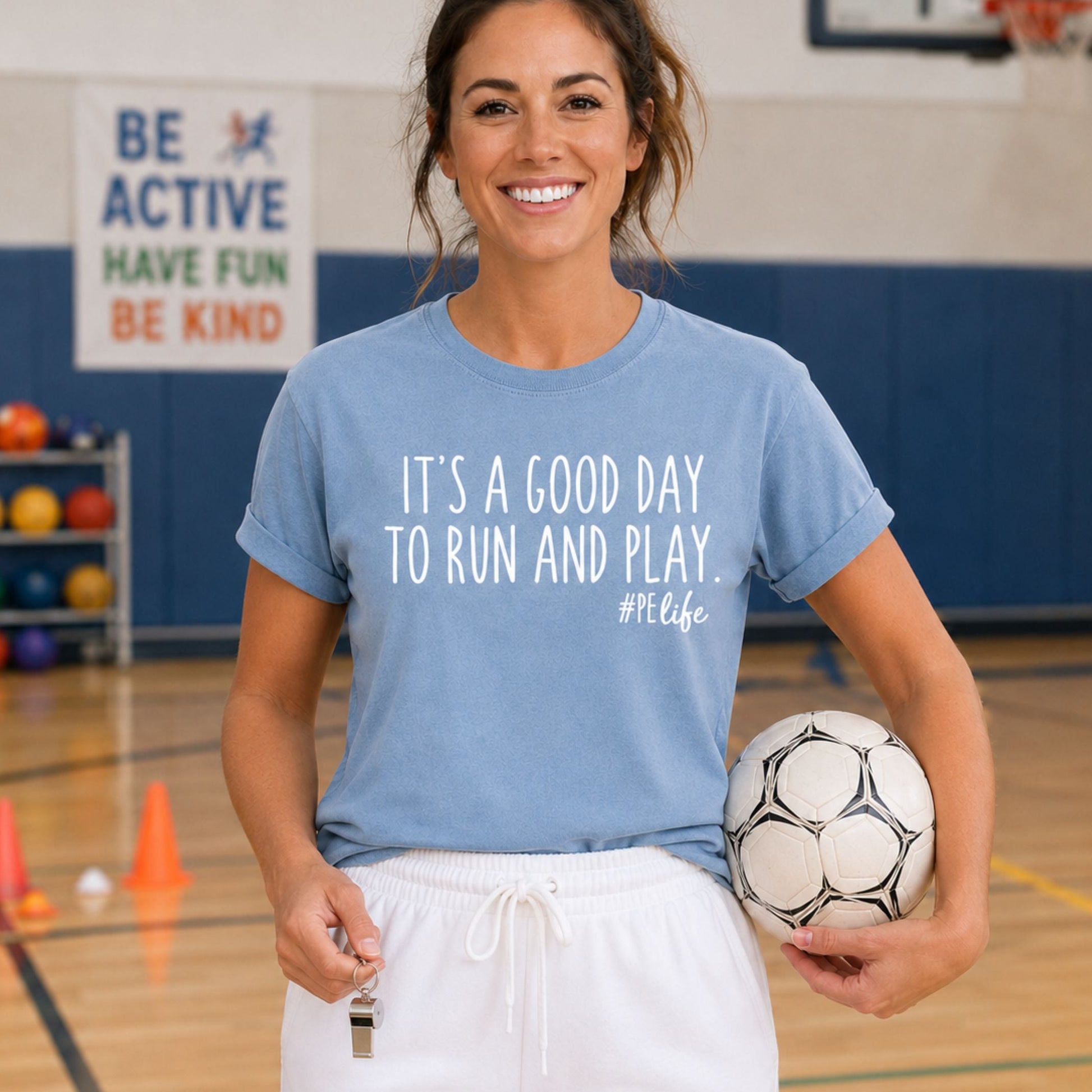 A woman wearing a blue jean comfort colors shirt that says It's a Good Day to Run and Play #PE life