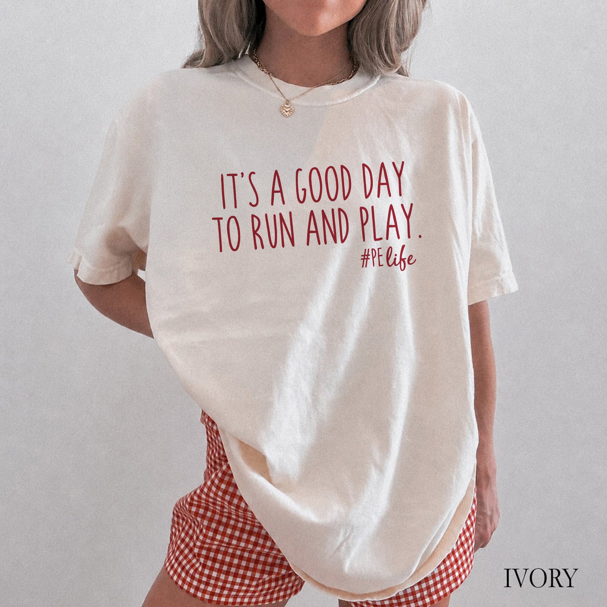 A woman wearing an ivory comfort colors shirt that says It's a Good Day to Run and Play #PE life