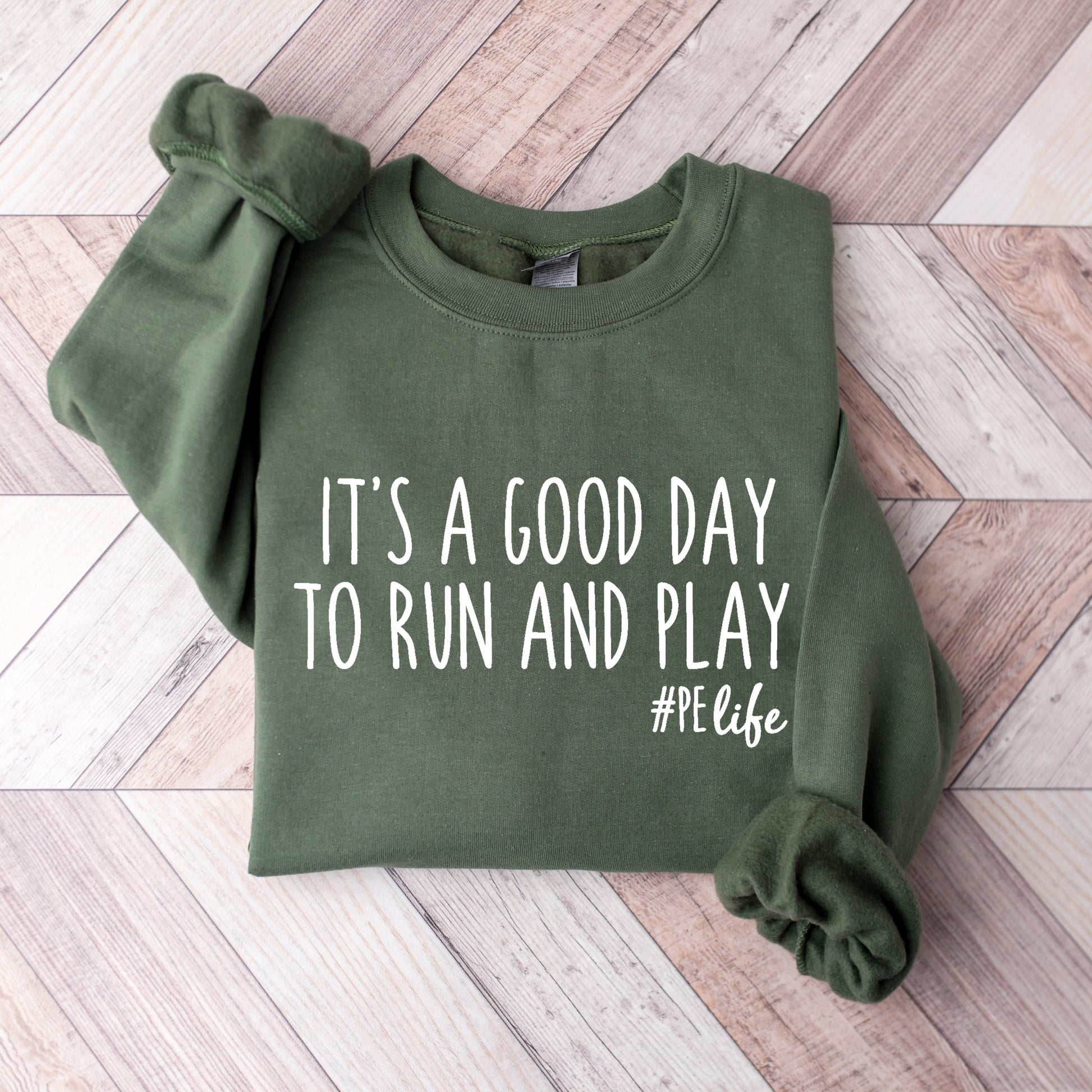 A military green Gildan sweatshirt that says It's a Good Day to Run and Play #PE life